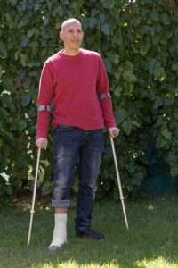 A man with a leg in plaster with two crutches.