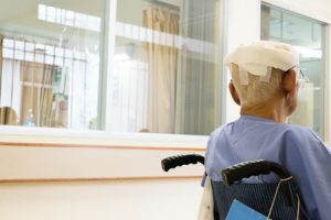 A person sat in the wheelchair with a bandaged head.