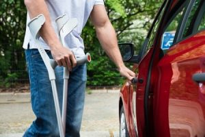 Injured man on crutches opening a car door