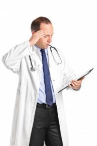 A doctor looking distressed as he reads a medical file.