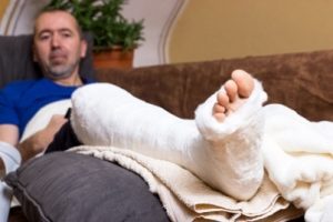A man sitting on a sofa with one leg in a cast.