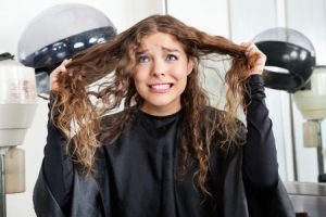 A woman in a hair salon holding her hair in distress