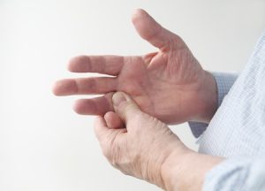 A man gripping at his hand that hurts due to nerve damage.