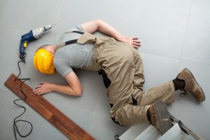 Worker lying on the floor after a defective work equipment accident caused them an injury. 