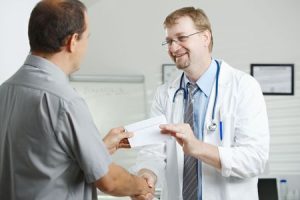 doctor handing a patient a sick note after they have had an accident at work. 