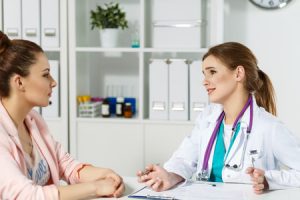 A doctor discussing with her patient about her the symptoms they are experiencing.