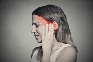 A woman holding her ear due to severe tinnitus