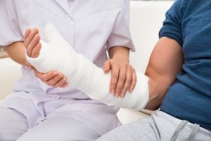 A patient with a broken wrist wearing a cast and sitting next to a nurse