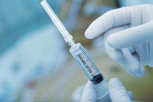 A medical professional holding a syringe. 
