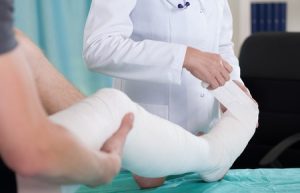 A medical professional putting a bandage over a fractured kneecap.