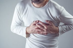 A man holding the left side of his chest in pain.