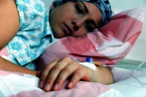 A woman asleep in bed with a canula coming from the hand.
