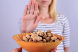 Bowl of nuts in front of a woman holding her hand up in a stop gesture. 