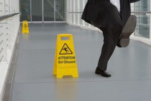 Man slipping over on wet floor near a wet floor warning sign