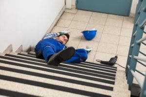 An employee who lays injured on the floor after he fell down the stairs at work.