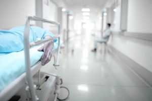 A person on a hospital gurney in a brightly lit corridor. 