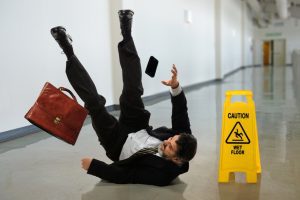 A man slipping next to a wet floor sign