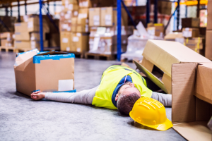 A man lying on the floor after suffering an injury from falling boxes.