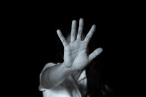 A black and white picture of a person holding their hand up and turning their head away.