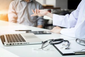 Doctors in discussion at a desk with a laptop, a clipboard and a stethoscope