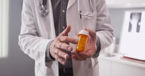 a doctor in a white lab coat pointing to a pill bottle containing wrongly prescribed antidepressants