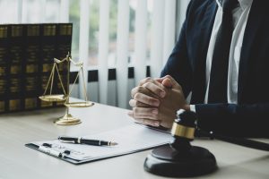 A Personal Injury Lawyer Sits At A Desk With Folded Hands. 