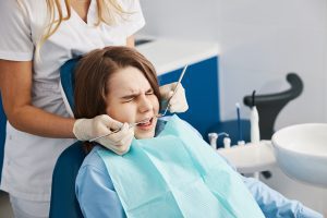 A young girl winces in pain as a dentist treats her