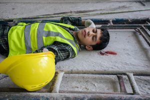 A man bleeding and unconscious from one or more head and brain injuries due to a fall at work.