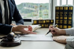 A Solicitor And Client Discuss A Case At A Desk. 