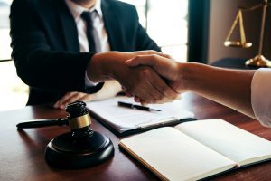 A food allergy solicitor shakes a client's hand over a table. 