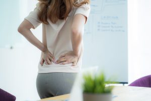 A woman holds her lower back in pain after suffering a nerve injury