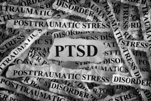 White pieces of torn paper with the words PTSD and post traumatic stress disorder printed on them. 