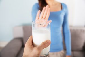 Woman holds up her hand in a stop gesture to a glass of milk. 