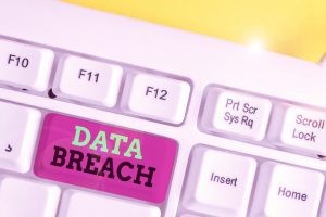The words 'data breach' written on the backspace of a keyboard. The backspace is bright pink, the word 'data' is in lime green and the word 'breach' is in black. 