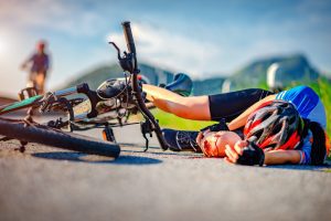 A cyclist lay sideways on the road behind their bike with a bleeding knee following an accident.