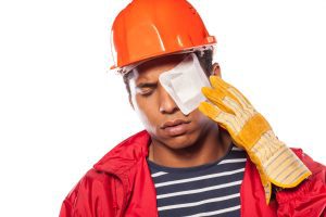 A construction worker with a bandage over their eye.