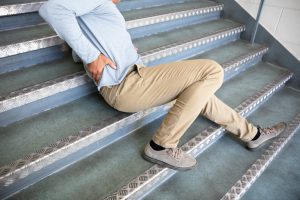 A man holding his back after falling down the stairs.