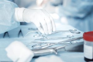 A surgeon reaches for a surgical instrument while performing an operation
