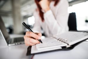 An employer recording injuries at work by filling in the accident book at work.