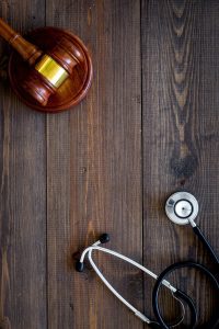 A gavel and a stethoscope on a wooden table. 