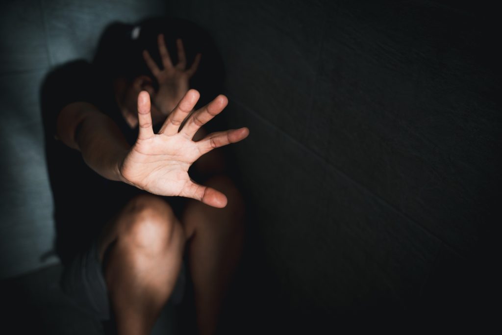 Girl sitting in corner dark room 