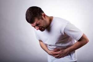 A man winces in pain while clutching their stomach after suffering from food poisoning on holiday.