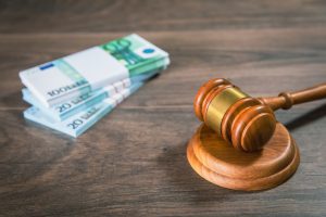 A stack of money notes on a desk next to a gavel to represent birth injury compensation.