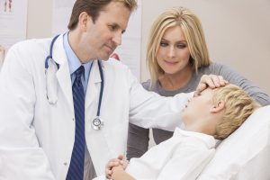 A doctor examines a sick child with his mother in attendance.