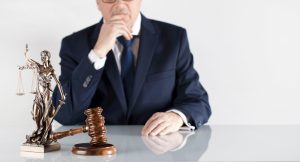 A fertility negligence solicitor sits behind a desk with a gavel and justice scale statue. 