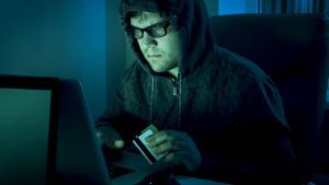A scammer holding credit cards on a computer