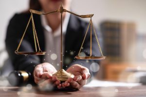 A solicitor holds scales with light reflections in front of scales and hands