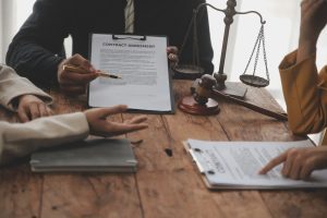 A no win no fee solicitor helps their client at a table with scales and a gavel 