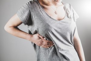 A woman holding the side of her ribs in pain