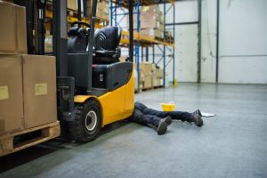injured person laying under a forklift truck in a warehouse